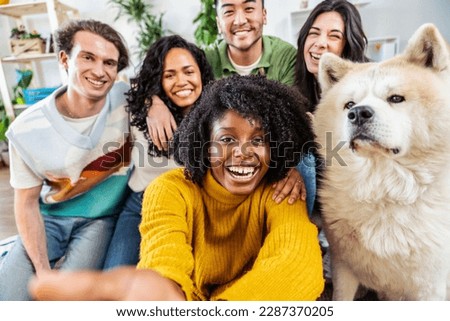 Multiracial group of friends with dog taking selfie picture together - Community of diverse young people smiling looking at camera - Friendship concept with guys and girls having fun indoors