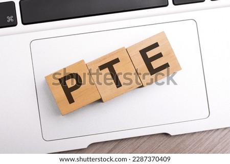 wooden blocks with letters PTE - Pearson Tests of English - on keyboard laptop