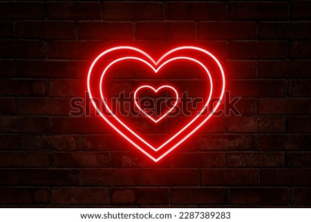 Neon red hearts on brick wall background.