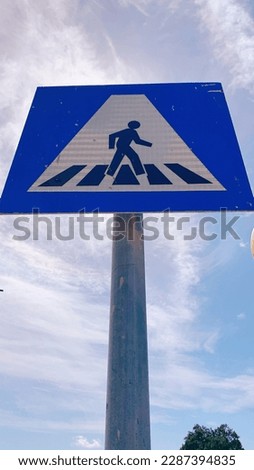 Crosswalk sign for pedestrians with light blue sky background