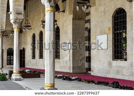 The entrance to the old historical Habibi Neccar mosque from the courtyard in Antakya (Hatay) Turkey and the shoes of the congregation before the earthquake of 2023. Selective focus, worship concept. 