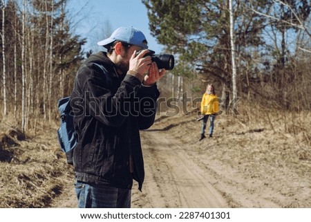 Man and girl photographed outdoors on sunny spring day. Two photographers outdoors.