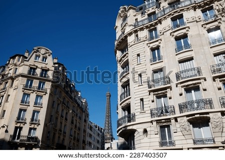 Traditional French houses with typical balconies and windows and Eiffel tower in the background . Paris.