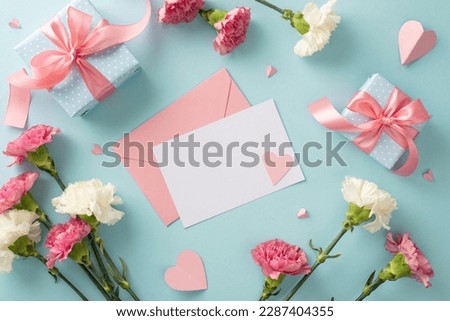Mother's Day happiness concept. Top view flat lay photo of empty postcard gift boxes with pink ribbons, carnation flowers, and pink paper hearts on pastel blue background with empty space for text
