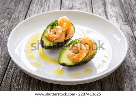 Avocado with fried prawns on and cocktail sauce on wooden background  Royalty-Free Stock Photo #2287413625