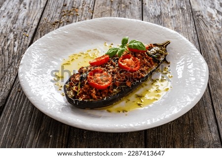 Roasted aubergine stuffed with minced meat and cheese on wooden table  Royalty-Free Stock Photo #2287413647