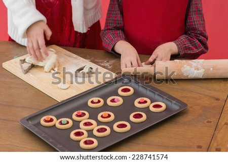 Festive little girls making christmas cookies on red background