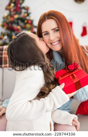 Daughter giving her mother a christmas present at home in the living room