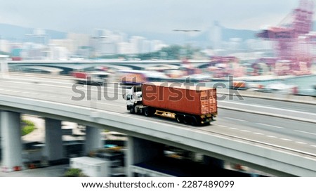 Container truck motion blur on highway overpass.