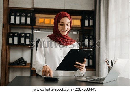 Young Arabic female entrepreneur wearing a hijab working online with a laptop at home office