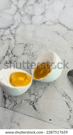 A photo showing the inside of a mature salted egg that is divided into two parts, the egg comes from a duck animal