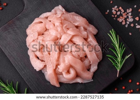 Raw chicken fillet cut into strips with spices and herbs on a wooden cutting board Royalty-Free Stock Photo #2287527135