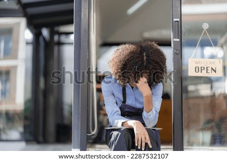 Barista Startup Coffee Shop African American female entrepreneur sitting sadly at the door of the coffee shop with an open sign. waiting for customer service food and drink concept