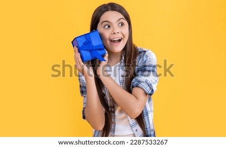 photo of amazed teen girl with birthday gift box. teen girl with birthday gift isolated on yellow.