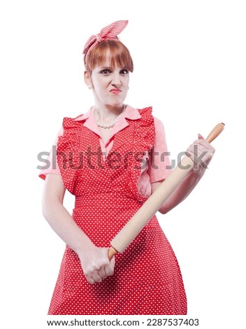 Aggressive angry vintage style housewife holding a rolling pin and looking at camera Royalty-Free Stock Photo #2287537403