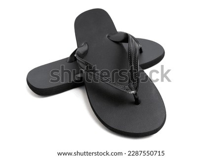 A close-up studio shot of a pair of black flip-flops isolated against a white background. Royalty-Free Stock Photo #2287550715