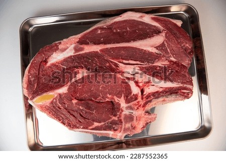 Raw cowboy steak with seasonings on white background, prime rib eye on bone