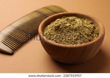 Henna powder and comb on beige background, closeup. Natural hair coloring