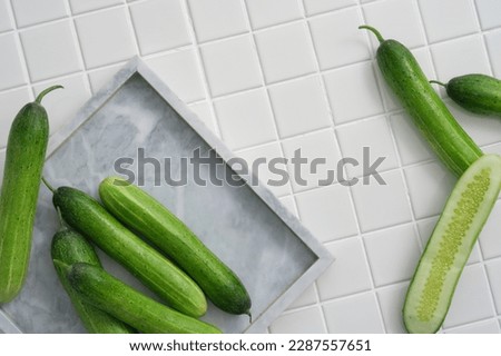 Many Cucumbers are decorated on a square marble tray and on mosaic tiles background. Cucumber (Cucumis sativus) can be used in the manufacture of cosmetics. Copy space, empty are