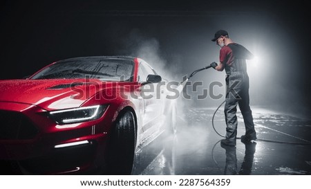 Portrait of an Adult Man Working in a Detailing Studio, Prepping a Factory Fresh Red Sportscar for Maintenance Work and Car Care Treatment. Cleaning Technician Using High Pressure Washer Royalty-Free Stock Photo #2287564359