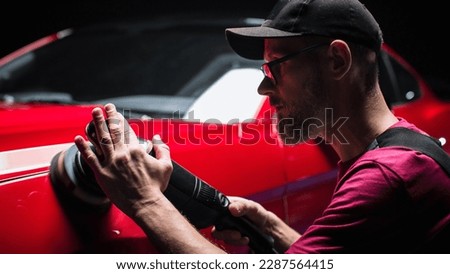 Portrait of an Adult Man Working in a Detailing Studio, Prepping a Factory Fresh American Sportscar for Car Care Treatment. Technician Polishing the Fender with a Polishing Machine Royalty-Free Stock Photo #2287564415