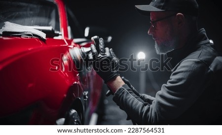 Red Sportscar Standing in a Stylish Detailing Dealership Studio. Professional Worker Buffing the Body from Light Scratches, Removing Swirls and Paint Defects from a Fender of the Vehicle Royalty-Free Stock Photo #2287564531