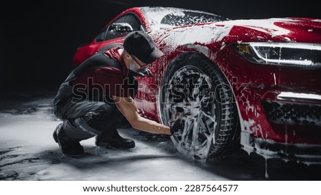 Red Sportscar's Wheels Covered in Shampoo Being Rubbed by a Soft Sponge at a Stylish Dealership Car Wash. Performance Vehicle Being Washed in a Detailing Studio Royalty-Free Stock Photo #2287564577