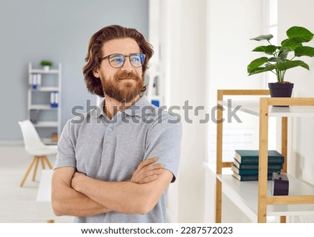 Portrait of confident satisfied business man looking away reflecting on good vision of future. Smiling Caucasian millennial bearded man in glasses and polo shirt poses with folded arms in office. Royalty-Free Stock Photo #2287572023