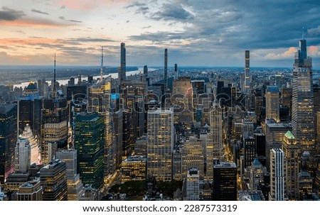 An illuminated midtown of New York City  and rainy clouds above in sunset.  Royalty-Free Stock Photo #2287573319