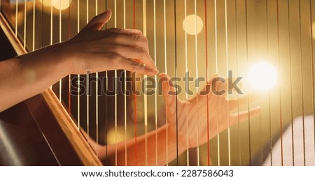 Cinematic Closeup of the Hands of a Female Harpist Playing Harp Solo Gracefully in a Dark Stage. Professional Musician Rehearsing Before the Start of a Big Show Royalty-Free Stock Photo #2287586043