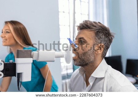 Man performing pulmonary function test and spirometry using spirometer at medical clinic. Spirometry of lungs Royalty-Free Stock Photo #2287604373