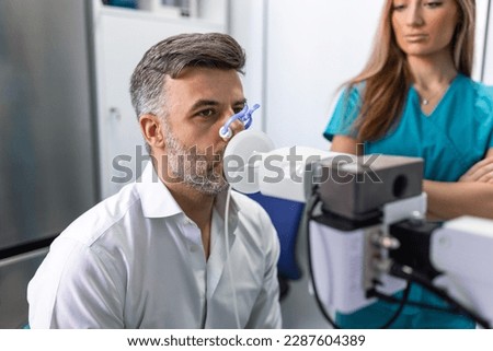 Adult man testing breathing function by spirometry having health problem. Diagnosis of respiratory function in pulmonary disease. Royalty-Free Stock Photo #2287604389
