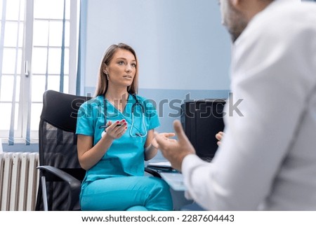 Serious man consulting with young female physician doctor at checkup meeting in hospital. Skilled general practitioner giving healthcare medical advices to patient.