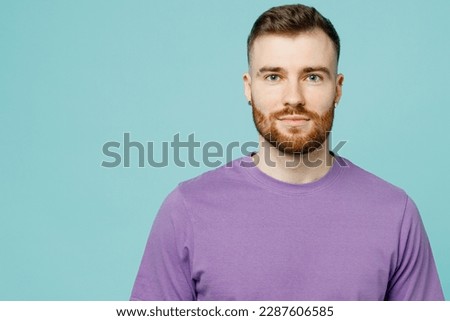 Close up young stylish cool caucasian european bearded unshaven man he wearing purple t-shirt look camera isolated on plain pastel light blue cyan color background studio portrait. Lifestyle concept Royalty-Free Stock Photo #2287606585