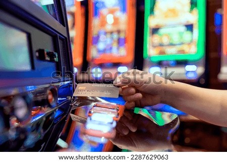 Slot Machine gambling bet Play Time. Female Gambler Hand hold credit card ready to win the game with one best shot casino close up female Hand holding credit card playing slot machine gambling closeup Royalty-Free Stock Photo #2287629063