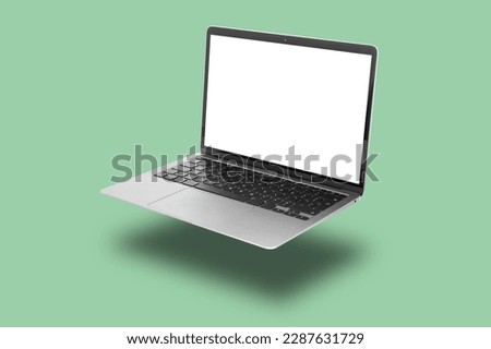 Modern laptop flying on pale light green background