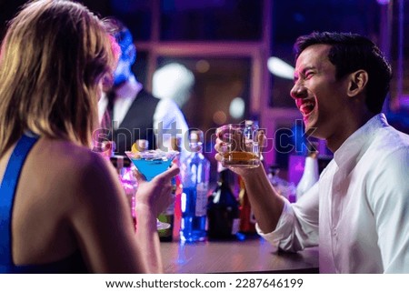 Beautiful young couple having fun, drinking alcohol cocktail in a bar. Attractive friends man and woman feeling happy and relax having a party, drink a glass of beer to celebrating event at night club Royalty-Free Stock Photo #2287646199