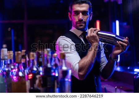 Caucasian profession bartender making a cocktail for women at a bar. Attractive barman pouring mixes liquor ingredients cocktail drink from cocktail shaker into the glass at night club restaurant. Royalty-Free Stock Photo #2287646219