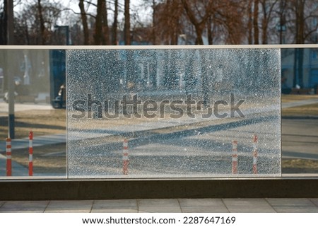 Damaged tempered glass fence. Broken glass fence with banisters. Broken guard rail on office terrace. Steel railing with damaged panel, cracks on broken tempered glass. Fencing repair Royalty-Free Stock Photo #2287647169