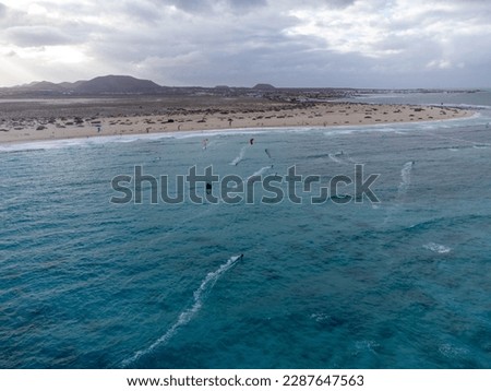 Aerial sunset view on white sandy Corallejo dunes, beach, ocean water waves and kite surfers at winter, Fuerteventura, Canary islands, Spain