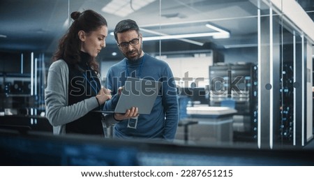 Portrait of Two Female and Male Engineers Using Laptop Computer to Analyze and Discuss How to Proceed with the Artificial Intelligence Software. Casually Chatting in High Tech Research Office Royalty-Free Stock Photo #2287651215