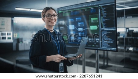 Portrait of a Beautiful Diverse Female Wearing Glasses, Using Laptop Computer, Looking at Camera and Smiling. Information Technology Specialist, Software Engineer or Developer Royalty-Free Stock Photo #2287651241