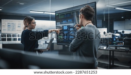 Two Diverse Software Developers Having a Meeting in a Conference Room. Female and Male Tech Industry Engineers Brainstorming Ideas for Their Neural Network Blockchain Startup Royalty-Free Stock Photo #2287651253