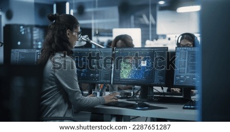Engaged Young Engineer Working on Computer in a Technological Office Environment. Beautiful Multiethnic Woman Writing Software Code for a Blockchain Project. Photo from the Back