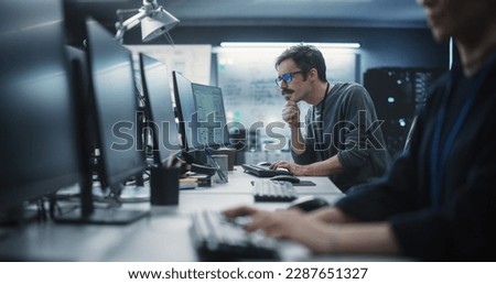 Portrait of a Thoughtful Engineer Working on Desktop Computer in a Technological Office Environment. Research and Development Department Writing Software Code for an Innovative Internet Project Royalty-Free Stock Photo #2287651327