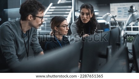 Team of Three Talented Young Software Engineers Use Computer to Discuss a Technological Project in Modern Industrial Office. Group of Male and Female Scientists Work in Research and Development Center Royalty-Free Stock Photo #2287651365