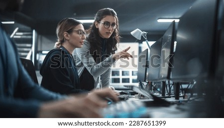 Two Beautiful Women Working in a Cyber Security Software Development Department. Young Manager Updating Software Developer on the Artificial Intelligence Safety Project Royalty-Free Stock Photo #2287651399