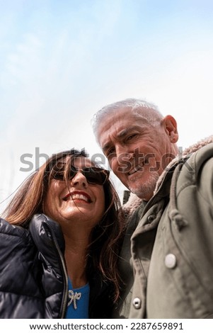 happy middle aged couple taking a selfie in front a dinosaur in a public park - vacation and traveling lifestyle concept