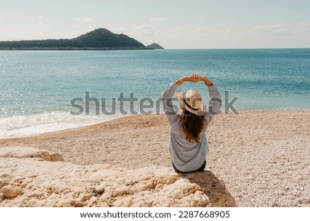Kaputas Beach Turkey - woman on the rock watching a beautiful sea view and a sandy beach below in summer time. Royalty-Free Stock Photo #2287668905