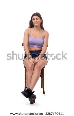 front view of a young girl sitting on chair with Stretched legs on white background Royalty-Free Stock Photo #2287670411